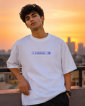 Person wearing a white t-shirt with a blue graphic design "Not About Her Again" against a cityscape sunset.