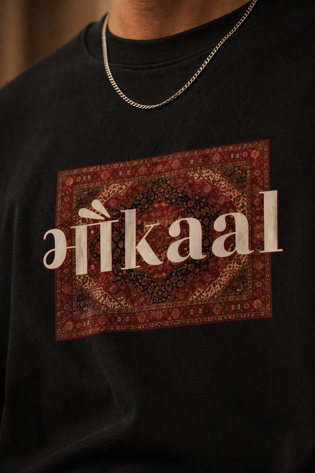 close up shot of black t-shirt with 'Bhaukaal' design on a person wearing a chain necklace.