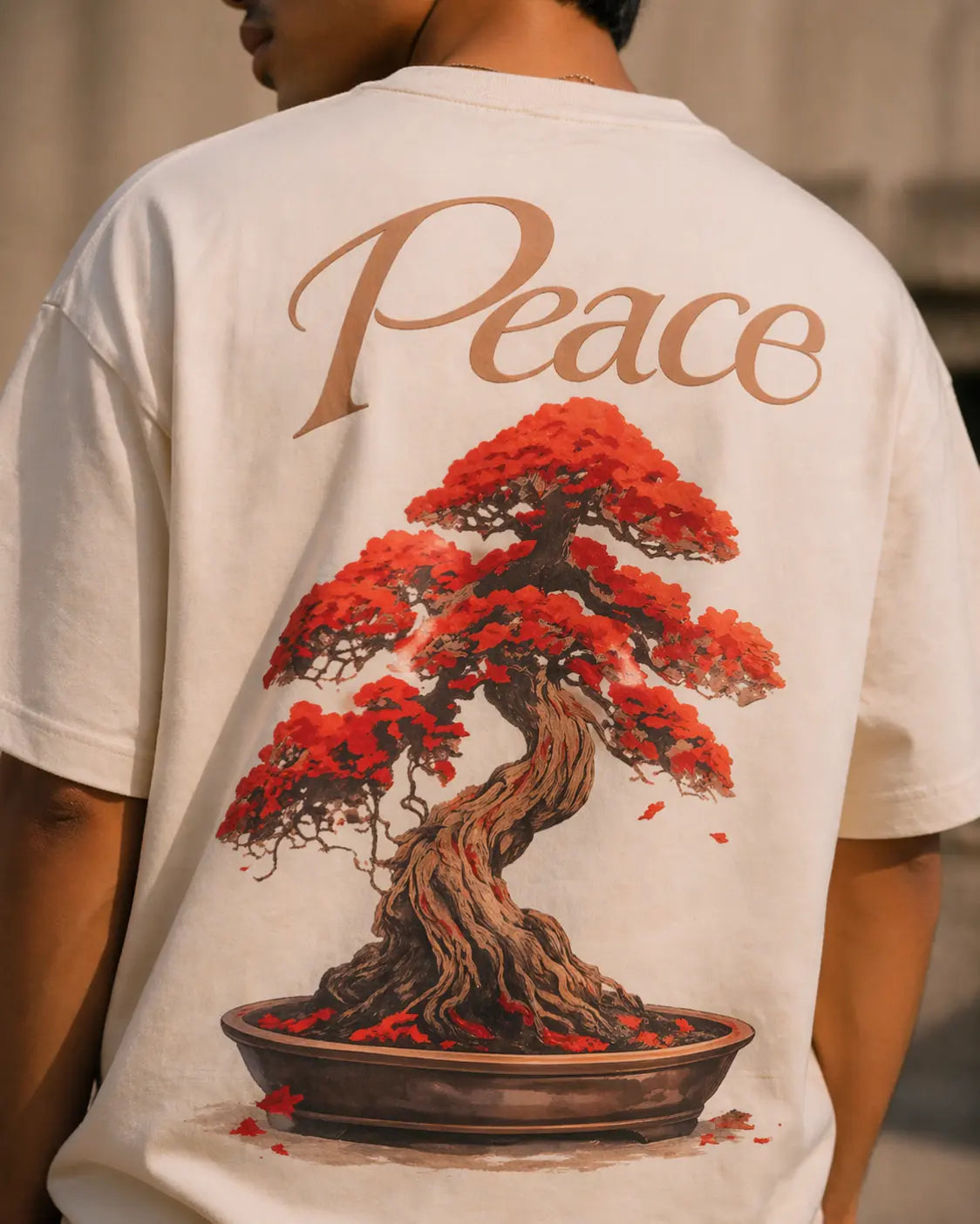 Close up of a person wearing a white t-shirt with a red bonsai tree design and the word 'Peace' on the back.